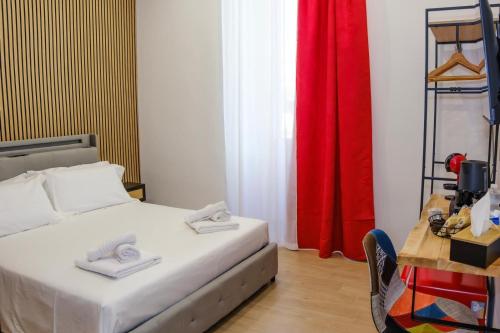 a bedroom with a bed and a table and red curtains at Futura Guest House in Bari