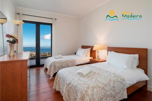 a hotel room with two beds and a balcony at OurMadeira - Villa Luz in Funchal