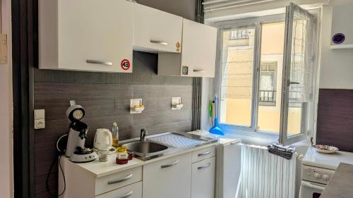 a kitchen with white cabinets and a sink and a window at appartement rénové-équipé en centre-ville in Le Puy en Velay
