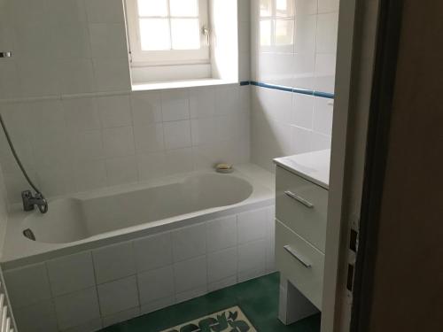 a white bathroom with a tub and a window at Chambres d'hôtes à Keraudy in Ploumilliau