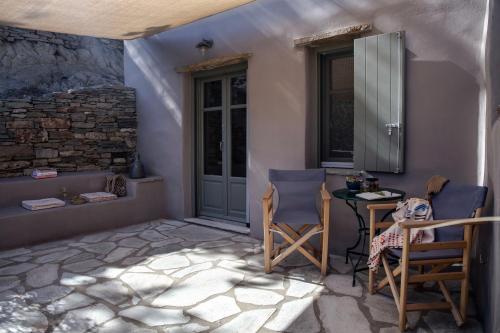 a room with two chairs and a table and a door at Under The Linden Tree Tinos in Xinára