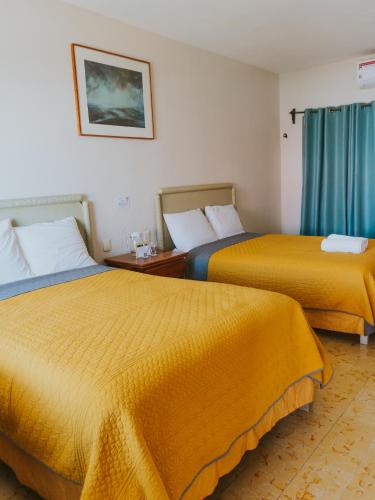 two beds in a hotel room with yellow sheets at Casa Chetumal Hotel in Chetumal