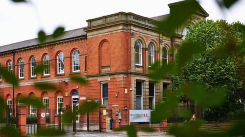a red brick building with a gate in front of it at Queen's Hospital Close near Birmingham City Centre in Birmingham