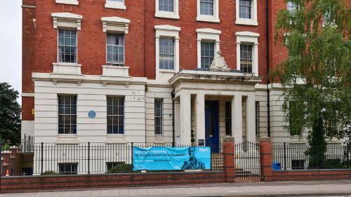 a red brick building with a blue sign in front of it at Queen's Hospital Close near Birmingham City Centre in Birmingham