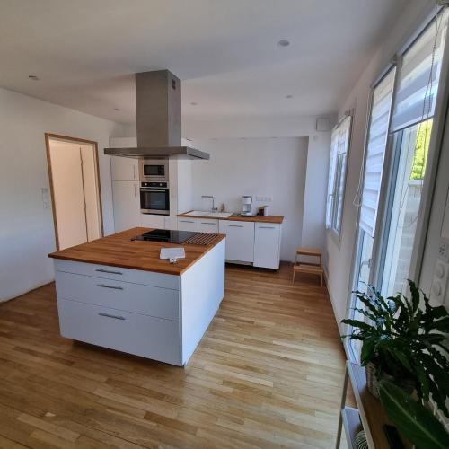 une cuisine avec des armoires blanches et un plancher en bois dans l'établissement Maison cosy avec Balnéo & jardin, à Châlons-en-Champagne