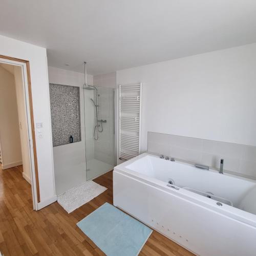 La salle de bains blanche est pourvue d'une grande baignoire et d'une douche. dans l'établissement Maison cosy avec Balnéo & jardin, à Châlons-en-Champagne