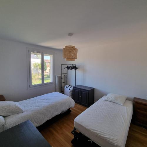 una camera da letto con due letti e una finestra di Maison cosy avec Balnéo & jardin a Chalons en Champagne