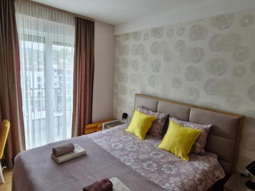 a bedroom with a bed with yellow pillows and a window at Gracia apartman in Vrnjci