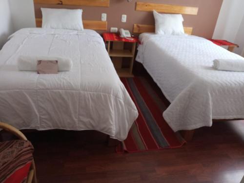 two beds in a hotel room with white sheets at kuntur inn hotel in Puno
