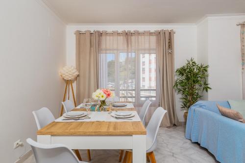a dining room with a table and a blue couch at Breeze Beach House in Setúbal