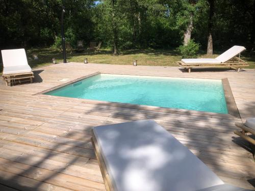 - une piscine avec 2 chaises longues et une table dans l'établissement Maison avec terrasse en bois et piscine, à Varaire