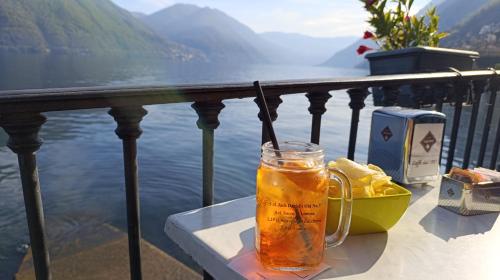 a glass of beer sitting on a table next to the water at Giò Giò House - Lake Como in Muronico