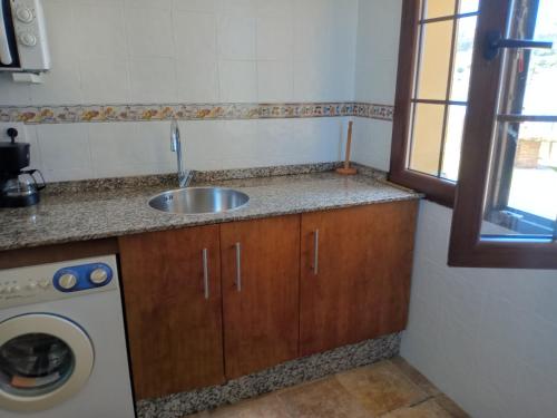 a kitchen with a sink and a washing machine at Casa de Aldea Misiego Rodiles in Selorio