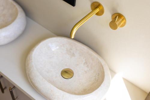 a bathroom with a white sink with a gold faucet at Huize Randenbroek Amersfoort in Amersfoort