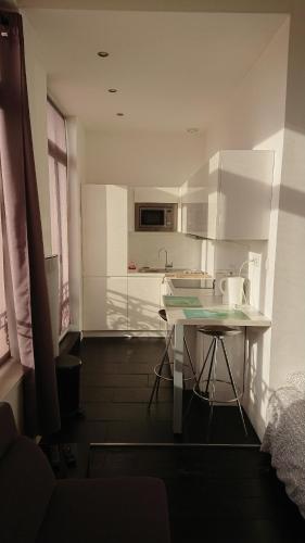 a white kitchen with a table and a counter at Studio Hypercentre proche gares et métro in Lille