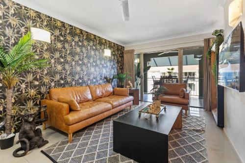 a living room with a couch and a table at Jungle Retreat Cairns - 9 Pools I Gym I BBQ in Westcourt