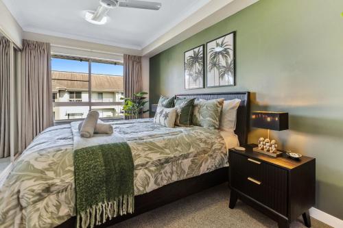 a bedroom with a large bed with a night stand at Jungle Retreat Cairns - 9 Pools I Gym I BBQ in Westcourt