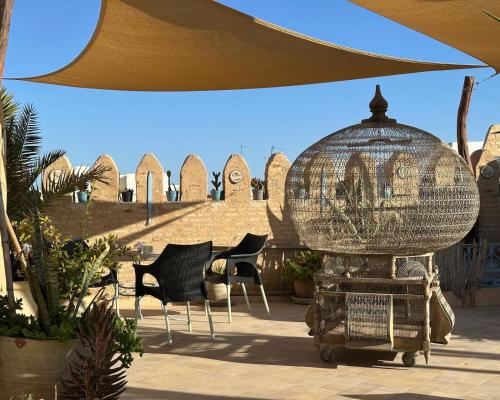 um pátio com cadeiras e uma gaiola para pássaros em Suite Dôme Jasmin em Bin Rhilouf
