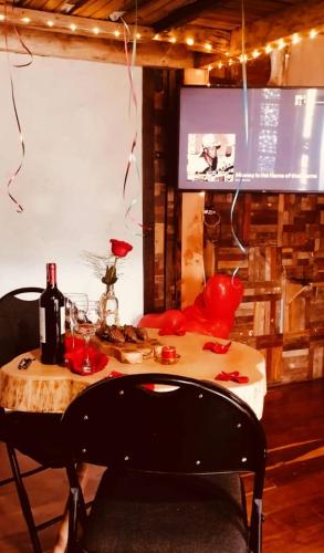 a table with a bottle of wine and a television at Cabaña en la Calera BersaNina in La Calera