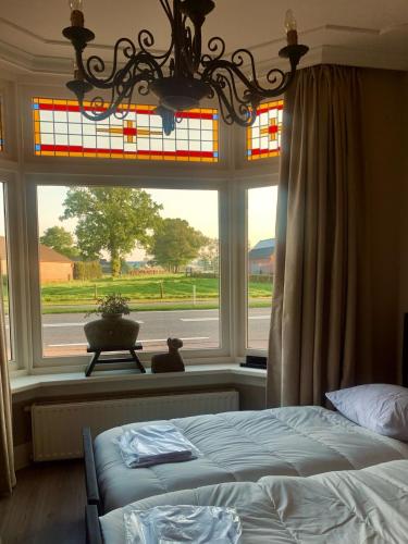 a bedroom with a bed in front of a window at Klassiek veluws huis onder de beuken in Barneveld