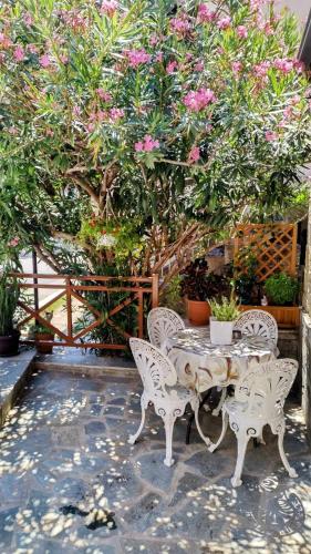 a table and chairs in front of a tree with pink flowers at Yiannis House in Kalabaka