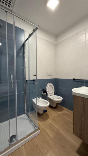 a bathroom with two toilets and a glass shower stall at Izz Home in Naples