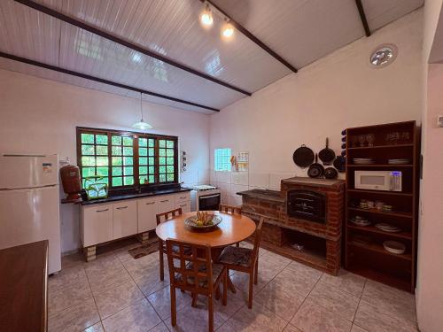 a kitchen with a table and a refrigerator and a window at Casa Amarela, Refúgio na natureza Rota do vinho in São Roque