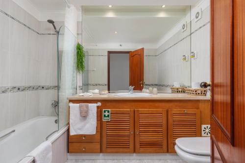 a bathroom with a tub and a sink and a toilet at Breeze Beach House in Setúbal