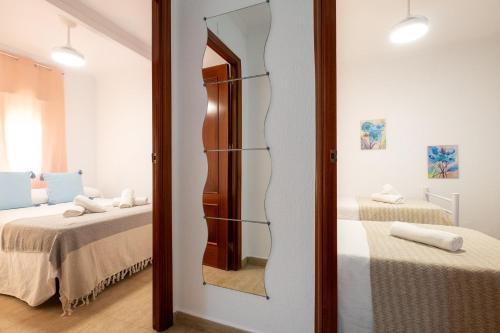 a mirror in a room with two beds at SunBeach- Apartamento cerca de la playa en Punta Umbría in Punta Umbría