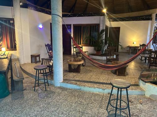 a room with a hammock and tables and chairs at Pura Vida Hostel in Tamarindo