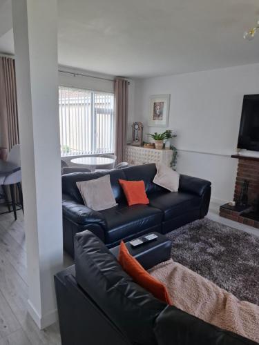 a living room with a black leather couch at Mourne Mountains holiday home in Newcastle