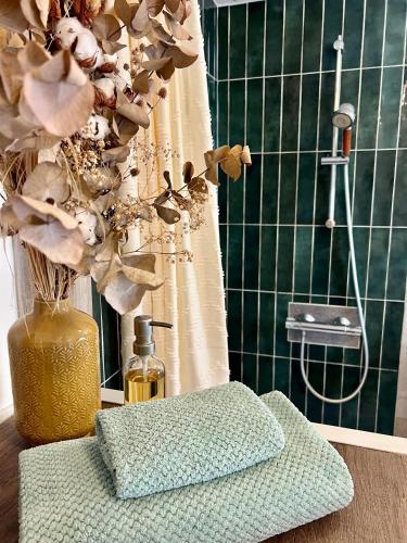 La salle de bains est pourvue d'une douche et d'un vase fleuri. dans l'établissement Le Cottage des Chalands, à Saint-Georges-sur-Cher