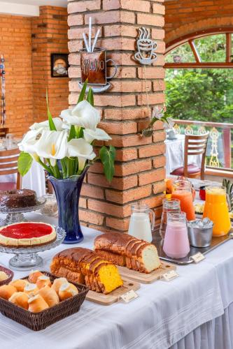 een tafel met brood en gebak en een vaas met bloemen bij Estalagem Spiller in Monte Verde