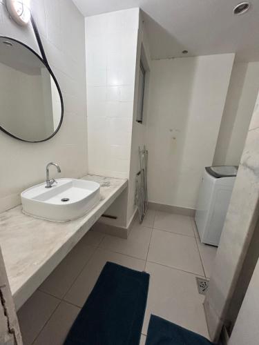 a white bathroom with a sink and a mirror at Apê Praia do Forte in Cabo Frio