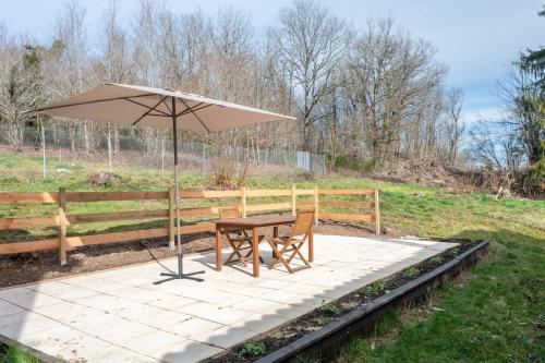 a table and an umbrella on a patio at charming nature lodge in Périgord in Négrondes