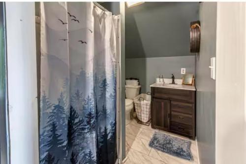 a bathroom with a shower curtain with trees and birds at Over Garage Apartment Studio in Lincolnton