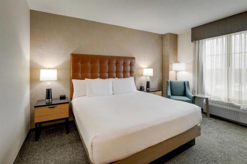 a bedroom with a large white bed and a chair at Drury Inn & Suites Montgomery in Montgomery