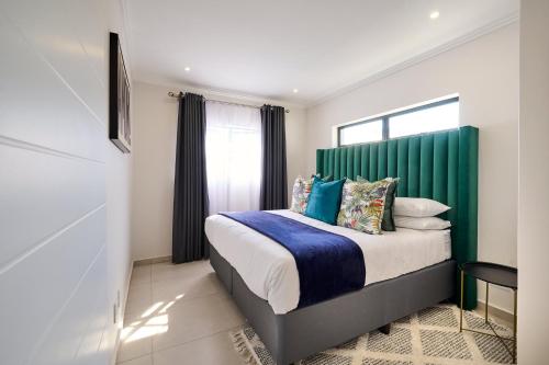 a bedroom with a bed with a green headboard at Craigavon Haven in Sandton