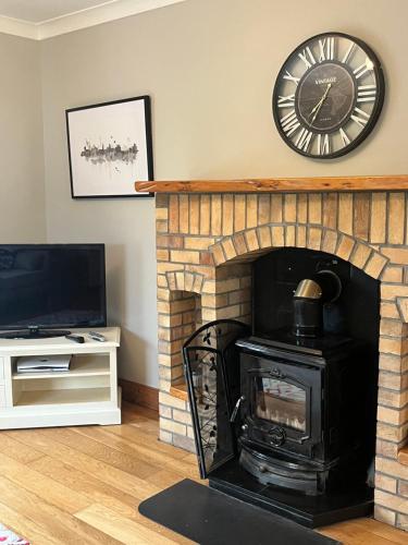 a living room with a fireplace with a clock on the wall at Killaneen in Ballinamore