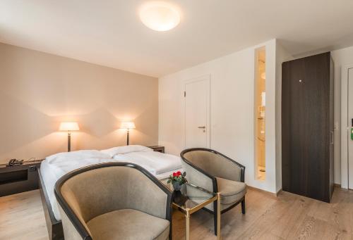 a hotel room with a bed and two chairs at Hotel Alpina Luzern in Luzern