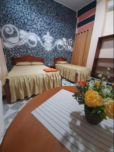 a room with two beds and a table with flowers at Hotel Oasis in Riberalta