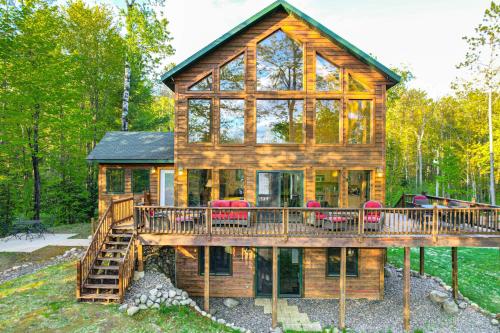 a log cabin with a deck and red chairs at Paddle Ready Hayward Lake View Retreat with BBQ in Hayward