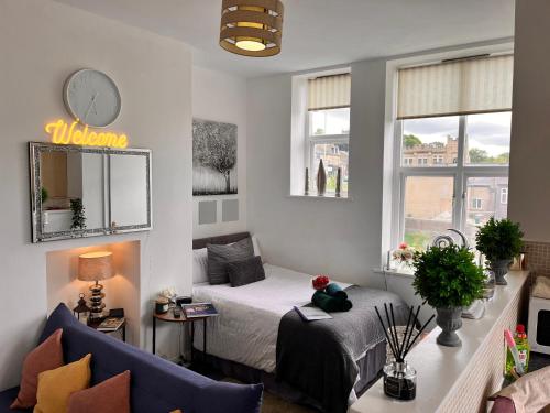 a bedroom with a bed and a couch and a clock at Luxurious Studio flat in Shipley Central in Shipley