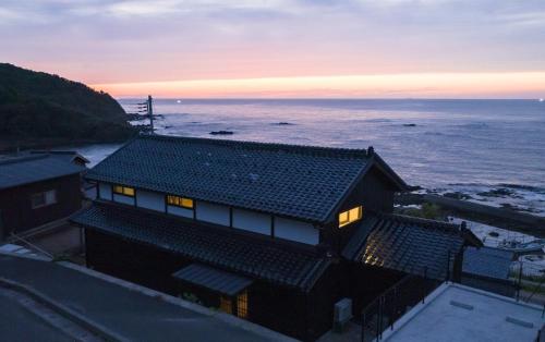 a house with a view of the ocean at sunset at Iso Ocean Breeze Villa in Kyotango