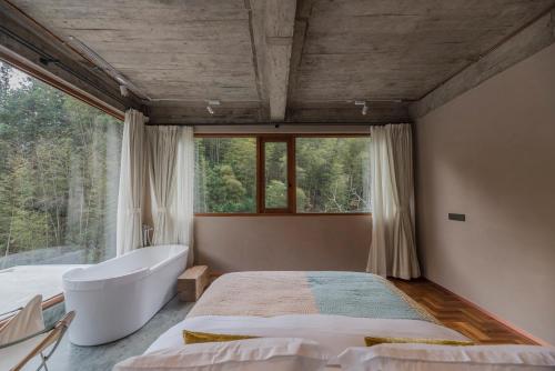 a bedroom with a tub and a bed and a window at Shanyu Life Huangshan Design Hotel in Huangshan