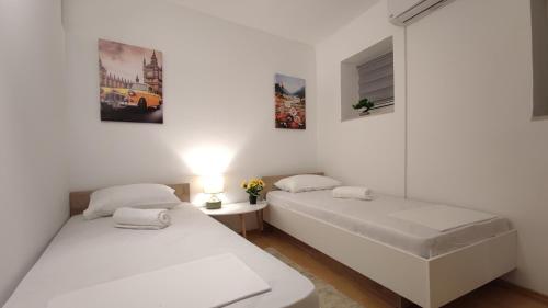 two beds in a room with white walls at Apartmani Tarik in Mostar