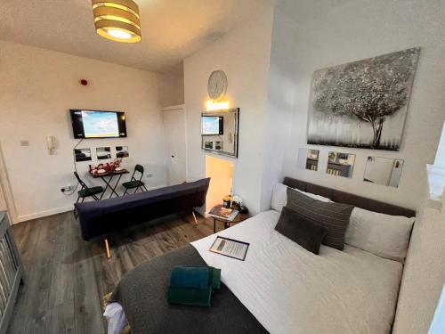 a living room with a white couch and a living room with a table at Luxurious Studio flat in Shipley Central in Shipley