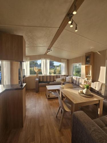 a kitchen and living room with a table and a couch at Chalet De VeerWater in Recreatiepark De Veerstal in Lathum