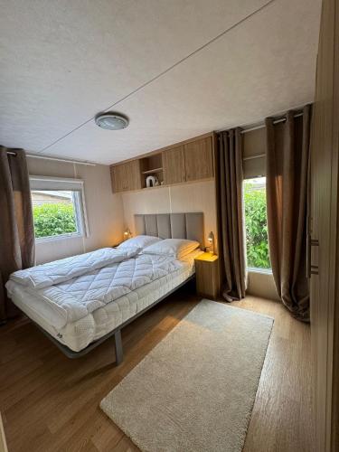 a bedroom with a large bed and two windows at Chalet De VeerWater in Recreatiepark De Veerstal in Lathum