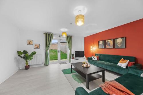 un salon avec un canapé vert et un mur rouge dans l'établissement Contractor & Family Friendly 4-BR House - Leads, à Cross Gates